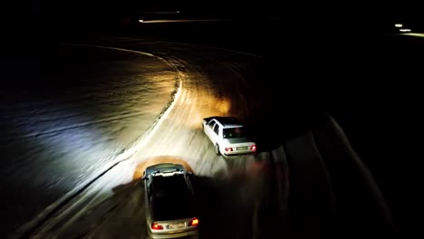 Seguimiento-Aéreo-Extremo-De-Autos-A-La-Deriva-En-La-Pista-De-Carreras-Durante-La-Noche-De-Invierno