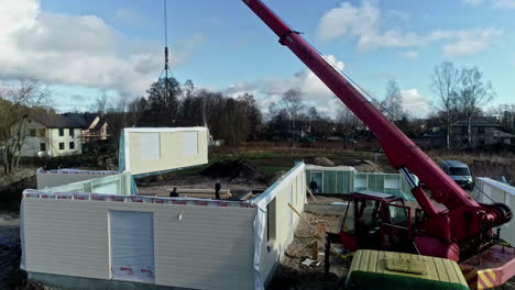 Crane-lifting-sandwich-type-walls-for-new-home,-aerial-drone-view