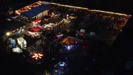 Parque-De-Atracciones-Navideño-Iluminado-En-El-Aparcamiento-Del-Barrio-Por-La-Noche-Vista-Aérea