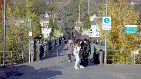 Menschen,-Die-An-Einem-Sonnigen-Herbsttag-Im-Herzen-Von-Meran---Meran,-Südtirol,-Italien,-über-Eine-Fußgängerbrücke-Laufen