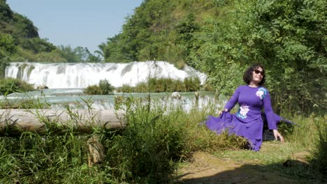 Turista-Femenina-Posa-Para-Fotografías-En-El-Hermoso-Fondo-De-La-Cascada