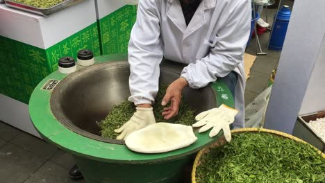 Chinese-woman-roasting-green-tea-in-a-large-bowl-on-a-street-of-Shanghai