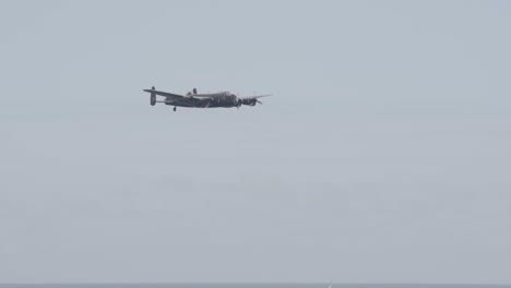 Avro-Lancaster-Flying-Over-Ocean-With-Sail-Boat-in-Background