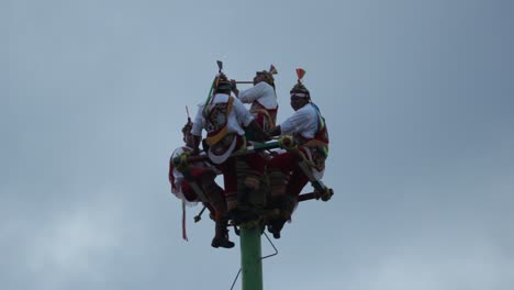 Nahaufnahme-Von-Papantla-Tänzern-Auf-Der-Spitze-Der-Stange,-Die-An-Einem-Bewölkten-Tag-Schlagzeug-Spielen