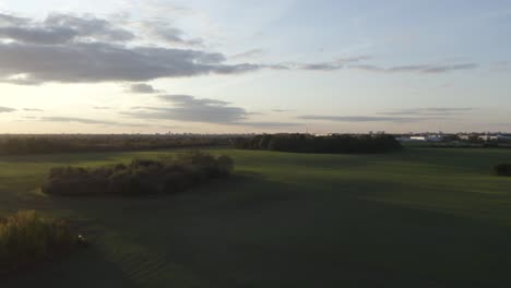 Eine-Filmische-Luftaufnahme-über-Einem-Wunderschönen-Feld-Während-Eines-Sonnenuntergangs