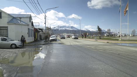 Avenida-De-Automóviles-En-La-Ciudad-De-Ushuaia,-Montañas-Nevadas-De-Fondo