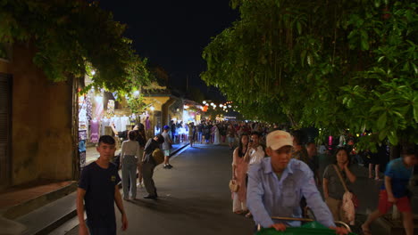 Toma-De-Pov-De-La-Gente-Local-Y-Los-Turistas-Recorrido-A-Pie-En-La-Antigua-Ciudad-De-Hoi-An-Decorada-Con-Linternas-De-Colores-Junto-Al-Río-Por-La-Noche,-Vietnam