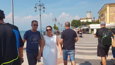 Tourists-enjoying-their-vacation-in-Lake-Garda,-Northern-Italy,-with-a-walk-by-the-harbor-on-a-sunny-September-day