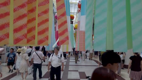 People-on-busy-street-walking-through-decorative-paper-streamers-during-Tanabata-festival-in-slow-motion