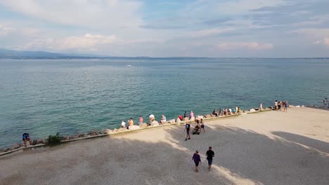 Turistas-Disfrutando-De-Un-Caluroso-Y-Soleado-Día-De-Septiembre-Junto-Al-Castillo-De-Sirmione-En-El-Lago-De-Garda,-Al-Norte-De-Italia