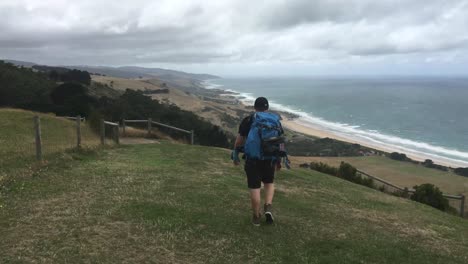 El-Joven-En-Un-Viaje-De-Aventura-Por-Carretera-Con-Mochila-Admirando-La-Vista-En-Una-Caminata-Por-La-Great-Ocean-Road,-Victoria,-Australia