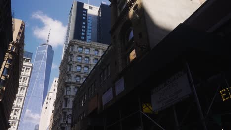 Pov-bottom-up-shot-in-road-of-New-York-City-showing-modern-One-World-Trade-Center-in-background---Beautiful-sunny-day-in-american-metropolis