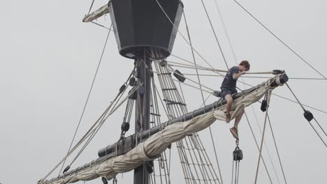 Ferdinand-Magellan-Nao-Victoria-carrack-boat-replica-mast-with-worker-fixing-the-sail-in-slow-motion-60fps