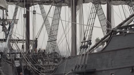 Galeón-Andalucia-Réplica-Detalle-Del-Barco-Toma-Inclinada-Con-Gente-Trabajando-Mientras-Está-Atracado-En-Valencia-En-Cámara-Lenta-60fps