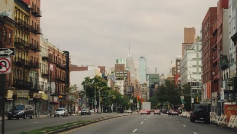 Pov-drive-by-car-on-Avenue-in-new-York-City-with-Skyscraper-in-background-during-cloudy-day---Slow-motion