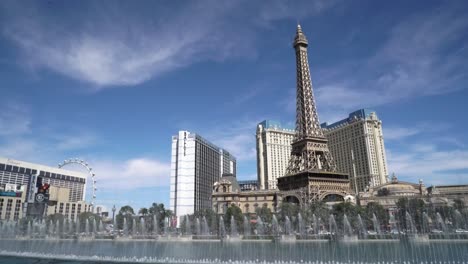 Las-Fuentes-De-Bellagio-Se-Muestran-Durante-El-Día-Soleado-En-Las-Vegas-Con-La-Torre-Eiffel-Al-Fondo-Y-El-Cielo-Azul.