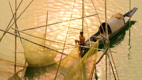 Junger-Fischer-Beim-Netzfischen-Auf-Einem-Boot-Im-Fluss-In-Der-Abenddämmerung