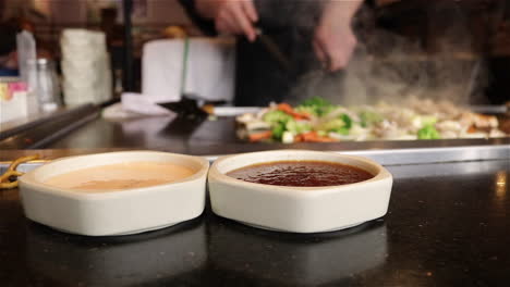 Japanese-Teppanyaki-chef-cooking-meat-and-vegetables-on-a-steaming-flat-top-grill