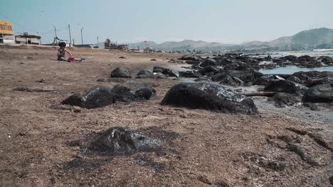 Un-Niño-Juega-Con-Arena-En-Una-Playa-Contaminada.