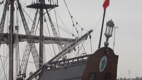 Galeón-Andalucia-Réplica-Detalle-Del-Barco-Toma-Inclinada-De-Bandera-Española,-Asta-Y-Espalda-Mientras-Está-Atracado-En-Valencia-En-Cámara-Lenta-60fps