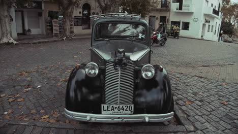 Auto-Clásico-Y-Antiguo-Estacionado-En-La-Calle-Uruguay-En-Costa-Colonia-Con-Motocicletas-Circulando-En-Cámara-Lenta