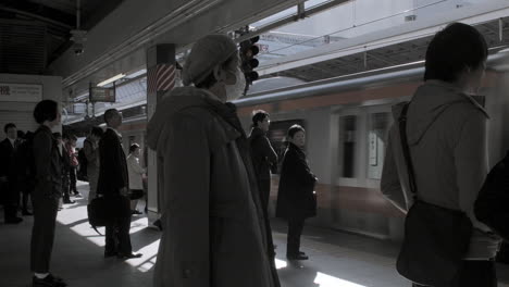 People-waiting-for-a-Yamanote-Line-train-at-arrive-at-the-platform-in-Tokyo,-Japan