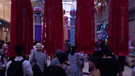 People-on-busy-street-walking-through-decorative-paper-streamers-during-Tanabata-festival-in-slow-motion