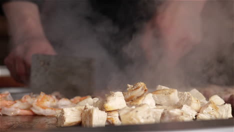 Chicken,-beef,-and-shrimp-steaming-on-a-flat-top-Teppanyaki-grill-at-a-Japanese-hibachi-style-restaurant