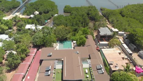 Aerial-tilt-down,-drone-shot-flying-over-large-Philippine-resort-and-pool,-near-the-ocean