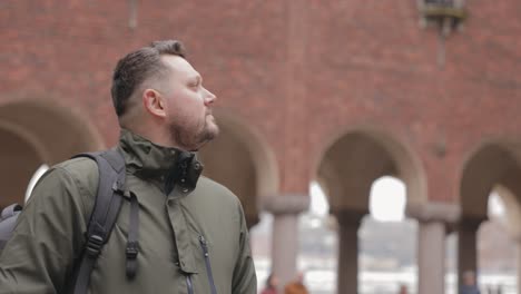 Young-Man-Looking-And-Admiring-The-Red-Brick-Building-Of-Stockholm-City-Hall-While-Standing-In-The-Inner-Courtyard