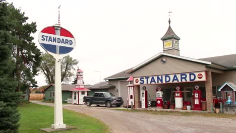 Vintage-rote-Krone-Und-Standard-Benzinpumpen-An-Einer-Alten-Tankstelle-Mit-Schild