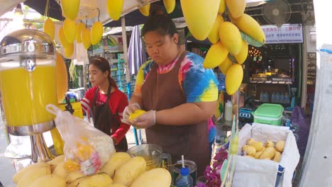 Zwei-Thailändische-Frauen-Schälen-Mangofrüchte-Und-Verkaufen-Frische-Säfte-Auf-Einem-Markt-Im-Freien