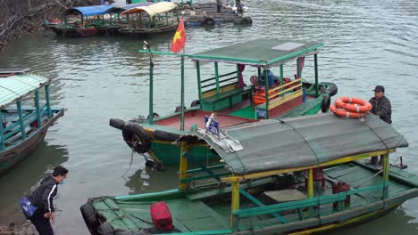 young-man-gets-on-a-traditional-wooden-taxi-boat-on-catba-island-in-vietnam