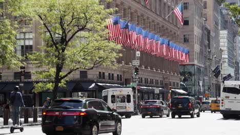 Muchas-Banderas-De-Estados-Unidos-En-Un-Edificio-Mientras-Hay-Mucho-Tráfico-En-La-Calle.