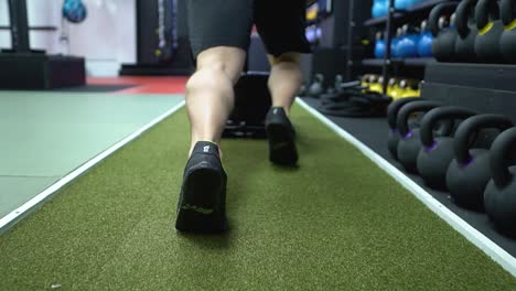 Un-Hombre-Fuerte-Está-Empujando-Un-Trineo-Merodeador-En-El-Gimnasio-Sobre-El-Suelo-De-Césped-Verde