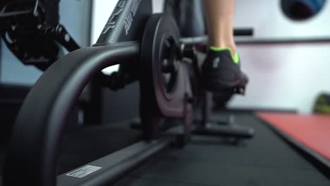 A-young-male-is-starting-pedalling-on-the-assault-air-bike-in-the-gym-for-warming-up-before-his-session