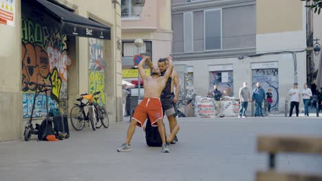 Street-performers-performing-spectacular-athletic-tricks-during-live-street-show-in-front-of-crowd-of-tourists-sitting-at-bars-and-restaurants-in-Barcelona,-Spain-during-sunset-on-warm-evening