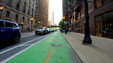 point-of-view-of-a-bike-ride-along-a-green-bike-path-in-the-city-metro-area-during-a-sunny-day