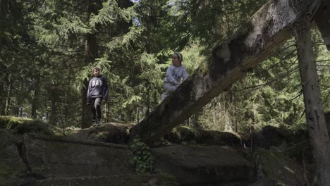 A-boy-and-a-girl-climbing-a-concrete-pillar-of-an-abandoned-building-in-the-forest