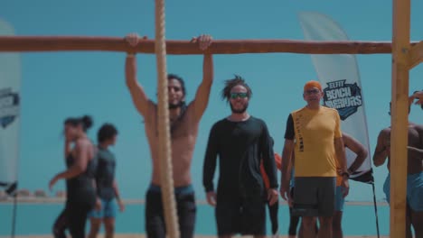 Un-Atleta-Hippie-Saltando-Y-Escalando-Saltando-Una-Barra-Alta-En-La-Playa---Cámara-Lenta