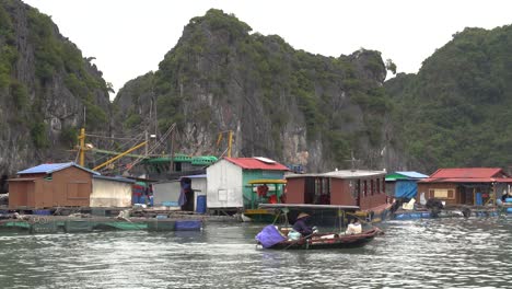 Mujer-Vietnamita-Remando-Un-Pequeño-Bote-A-Través-Del-Pueblo-Flotante-En-La-Bahía-De-Halong