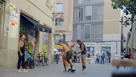 Street-performers-performing-spectacular-athletic-tricks-during-live-street-show-in-front-of-crowd-of-tourists-sitting-at-bars-and-restaurants-in-Barcelona,-Spain-during-sunset-on-warm-evening