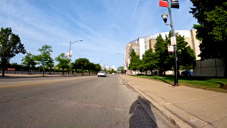 Punto-De-Vista-De-Hiperlapso-De-Un-Paseo-En-Bicicleta-Por-Un-Carril-Bici-Verde-En-El-área-Metropolitana-De-La-Ciudad-Durante-Un-Día-Soleado