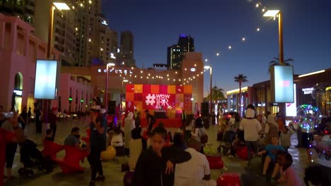 People-Gathered-In-Front-Of-The-Stage-Outside-The-Jumeirah-Beach-Residence-Building-In-Dubai,-UAE-During-An-Event-At-Dusk---tilt-up-shot