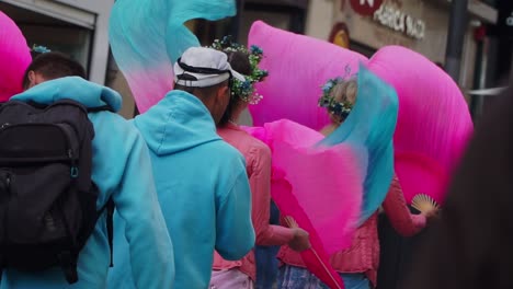 Toma-De-Enfoque-Medio,-Grupo-De-Artistas-Caminando-Por-Las-Calles-De-Oporto,-Mujeres-Vestidas-De-Rosa-Sosteniendo-Y-Agitando-Un-Abanico-Plegable.