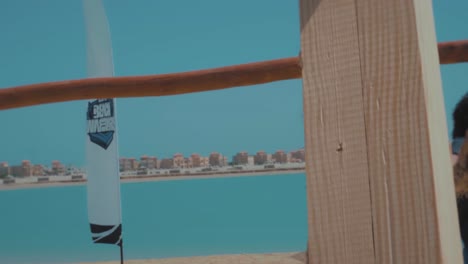 curly-young-man-flip-over-a-wooden-bar-by-the-beach---Slow-Motion