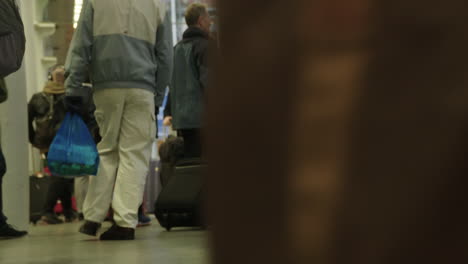 Static-shot-of-passengers-dragging-their-luggage-past-camera-in-a-very-busy-St-Pancras-International-Station-in-London