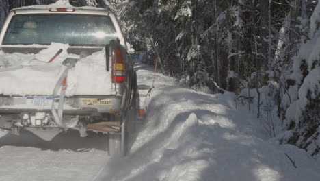 A-snow-covered-road-gets-cleared-by-a-gray-snow-truck-on-a-sunny-winter-day