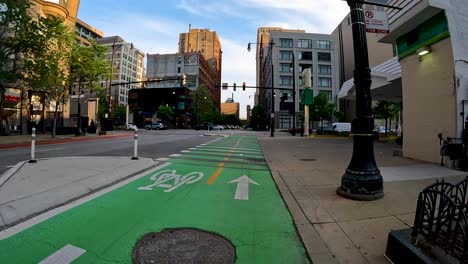 point-of-view-of-a-bike-ride-along-a-green-bike-path-in-the-city-metro-area-during-a-sunny-day