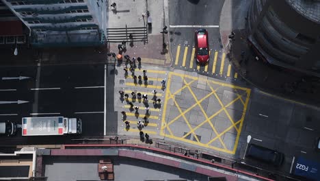 Las-Personas-Que-Cruzan-El-Carril-Peatonal-Amarillo-En-La-Intersección-En-Hong-Kong-Mientras-Los-Vehículos-Están-En-El-Carril-Se-Han-Detenido---Toma-Aérea